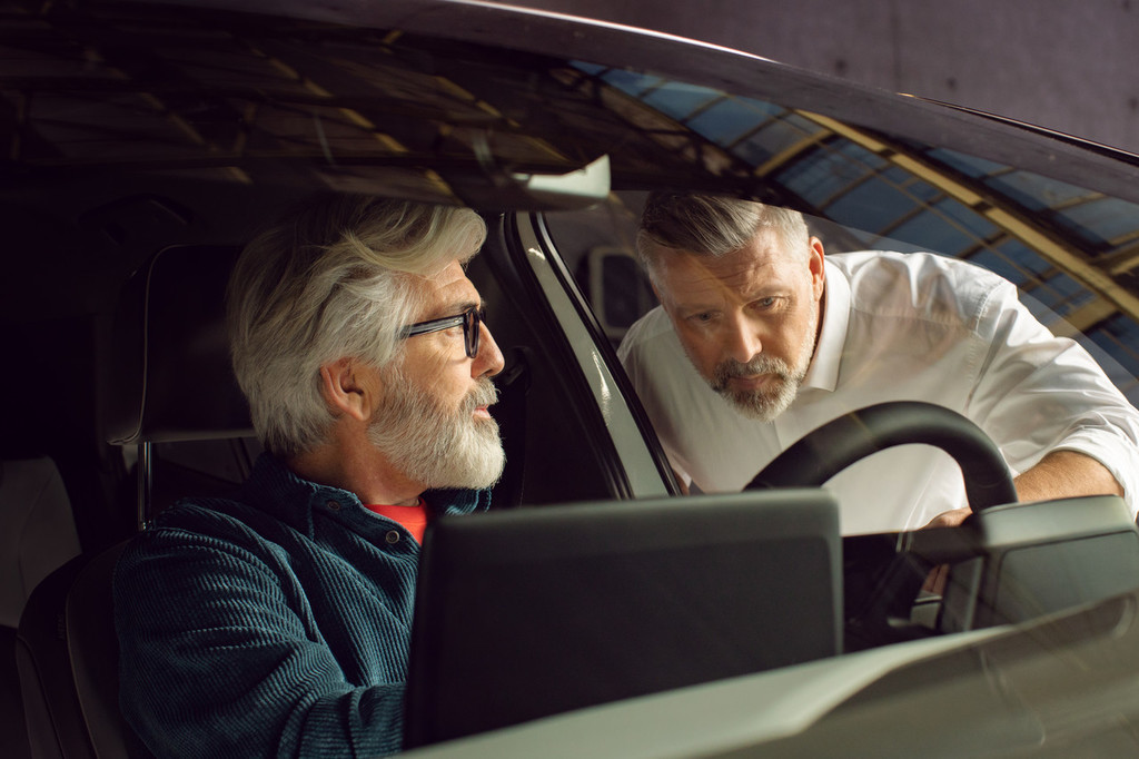Addetto alle vendite Volkswagen illustra la macchina al cliente seduto al volante