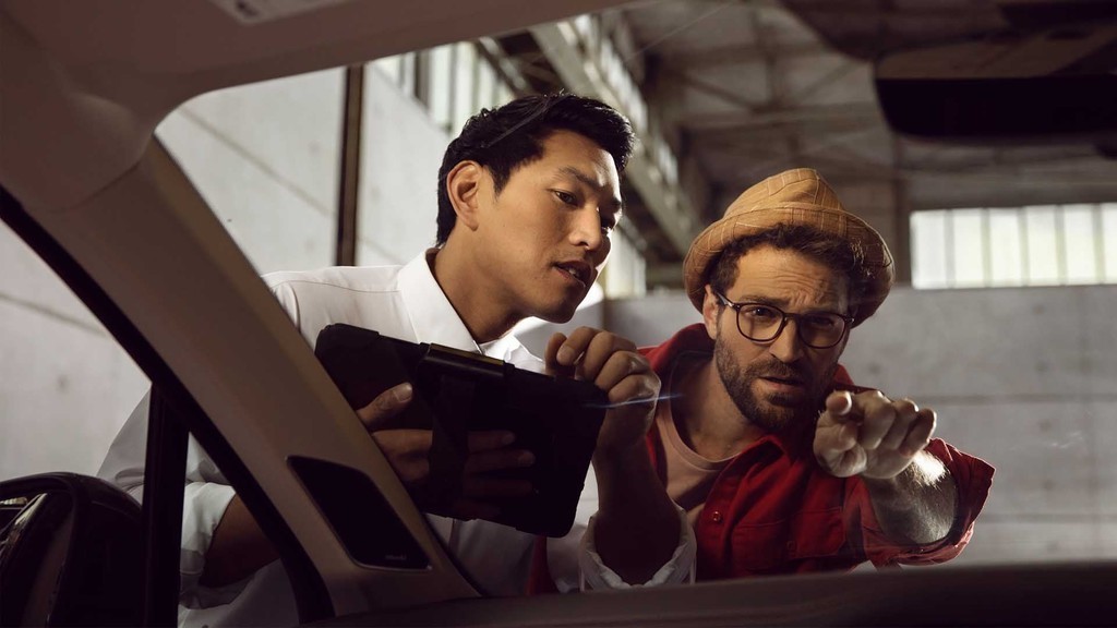 Un addetto Volkswagen controlla il parabrezza dell'auto insieme a un cliente.