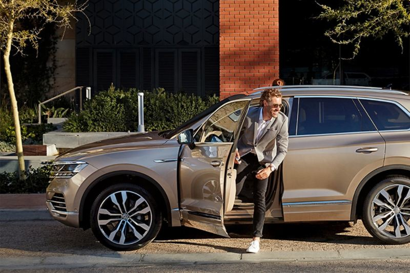 Un uomo scende dalla sua auto Volkswagen Business noleggiata