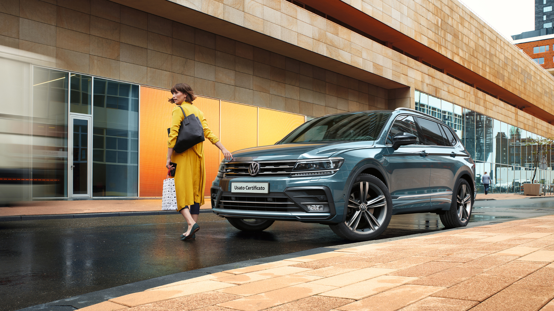 Donna accanto a Tiguan vista di 3/4 e parcheggiata in città