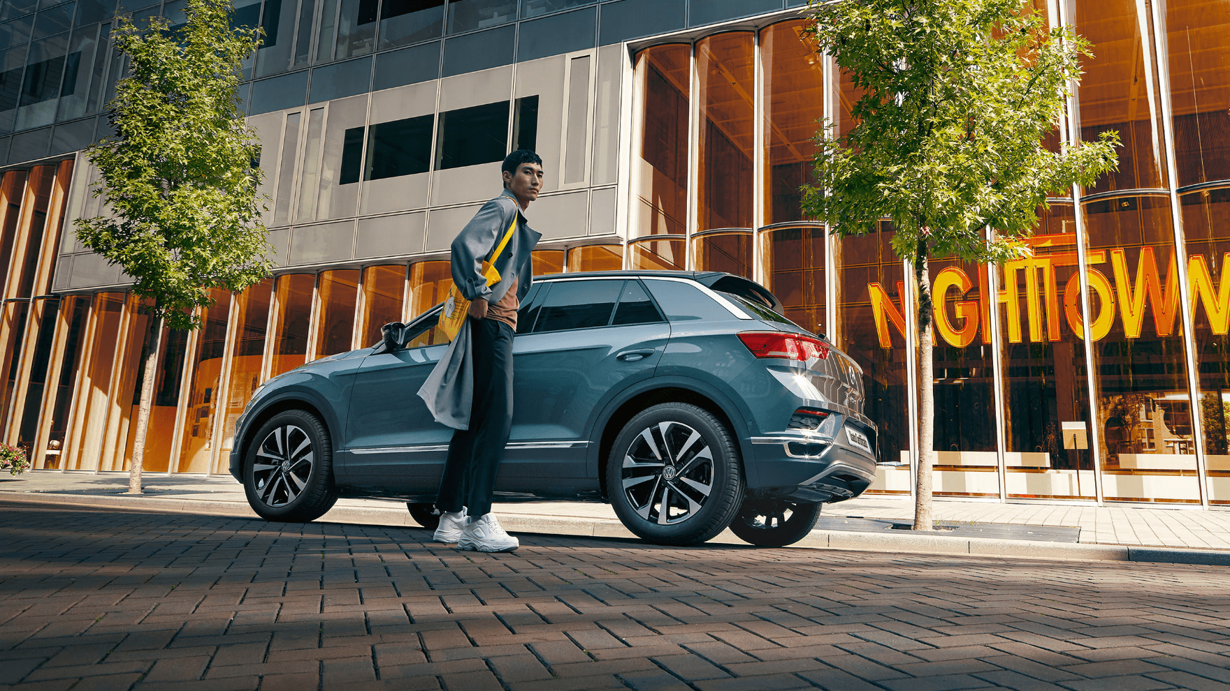 Coppia si tiene per mano allontanandosi da VW T-Roc parcheggiato in città