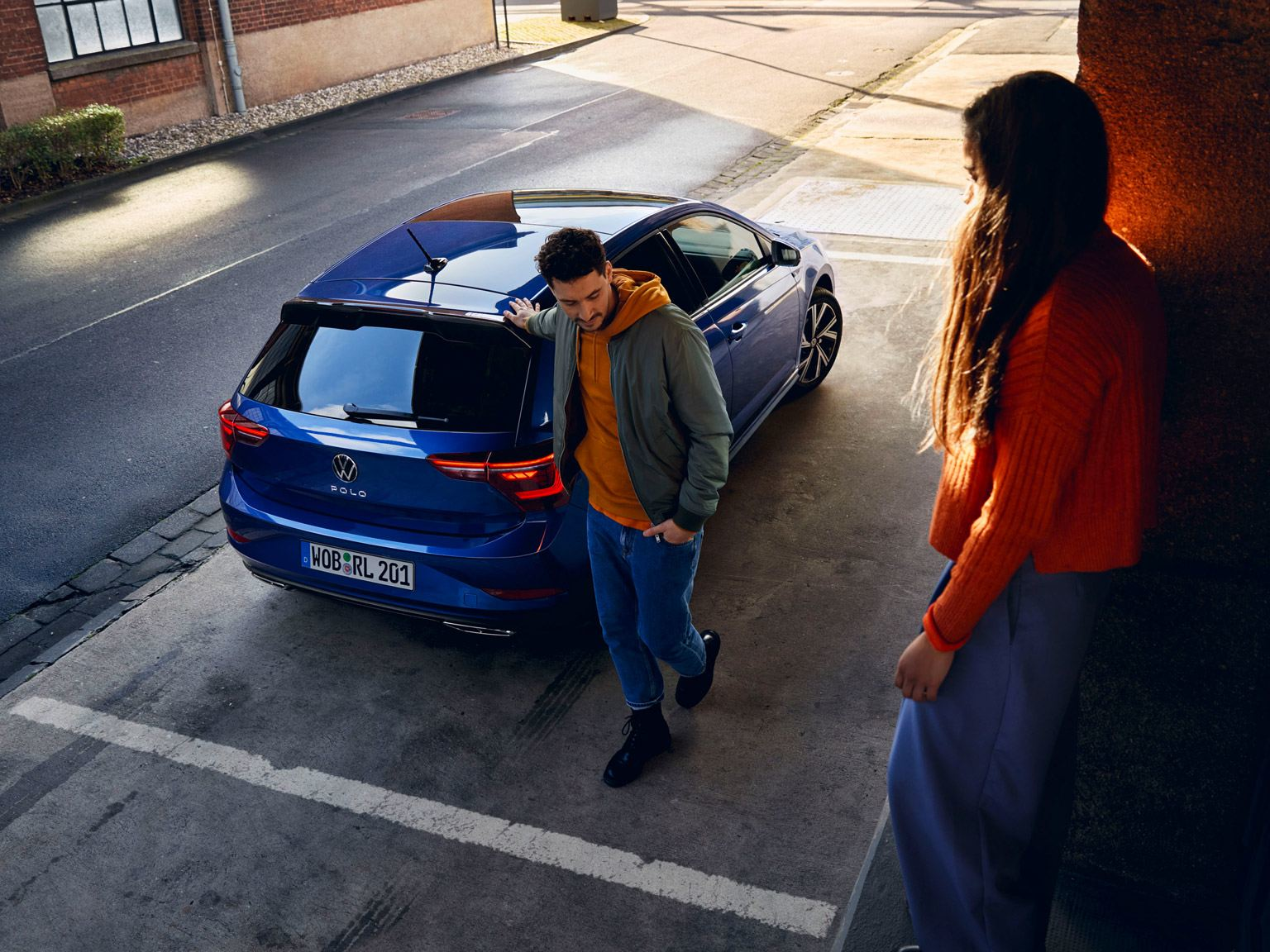 Uomo appoggiato alla Volkswagen Nuova Polo blu