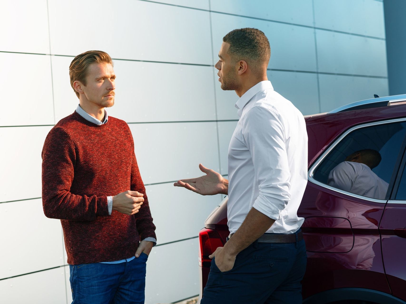 Due uomini discutono a fianco di una Volkswagen